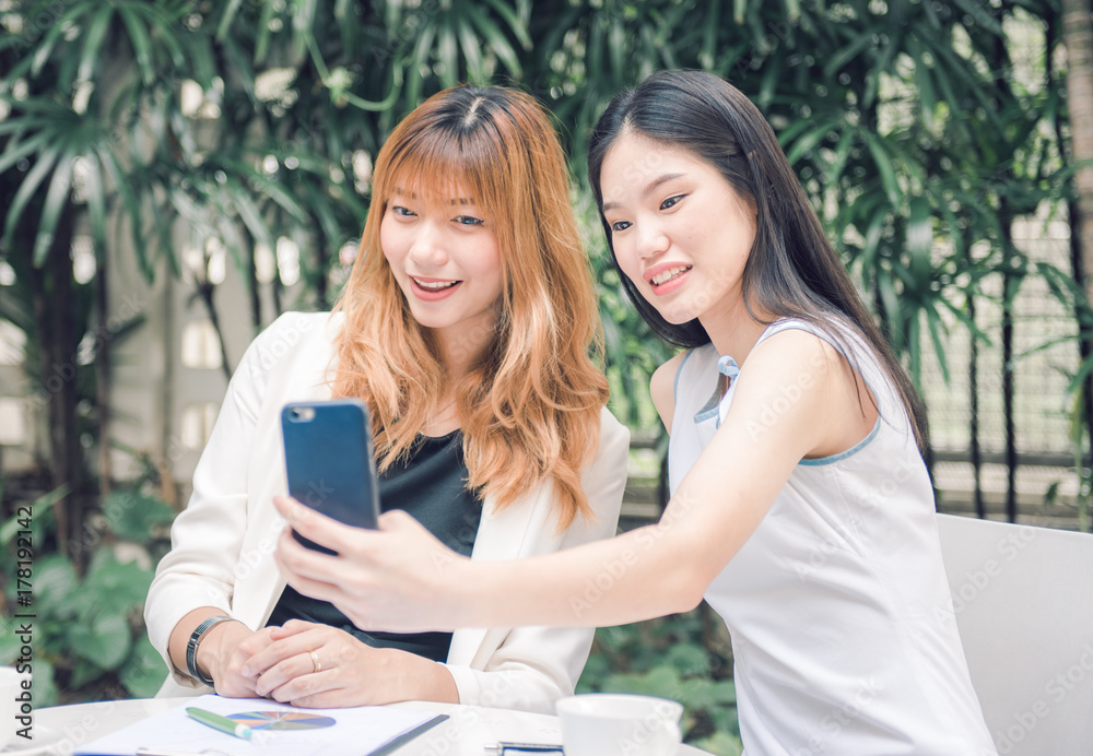 Two pretty young woman taking selfie from hand with smart phone and smiling in the garden, Urban life concept. Two pretty young woman taking selfie from hand with smart phone and smiling in the garden, Urban life concept.