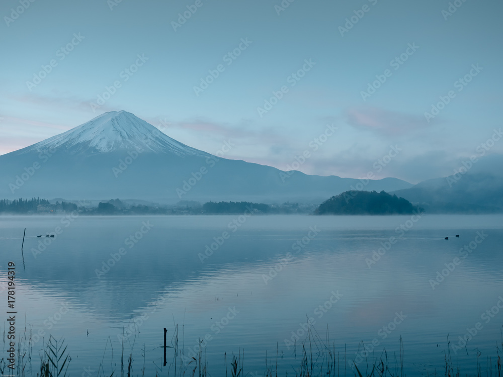 motion blur from  group of duck floating on lake foreground and fuji mountain background with fog and sunrise from japan
