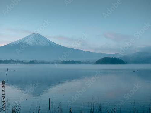 motion blur from group of duck floating on lake foreground and fuji mountain background with fog and sunrise from japan