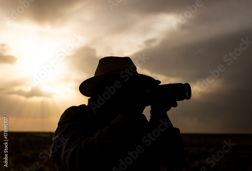 silhouette of a man with a camera on a sunset background © schankz