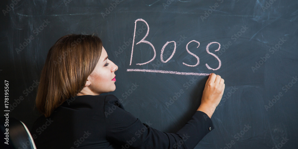 Business woman writing the word boss on desk. Female office worker put down text on black board. Banner Business woman writing the word boss on desk. Female office worker put down text on black board. Banner
