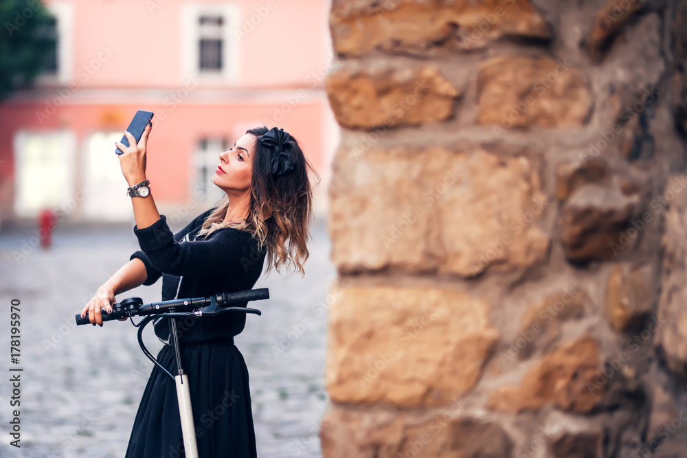Attractive young woman taking selfie on city streets. Portrait of young woman making faces at camera