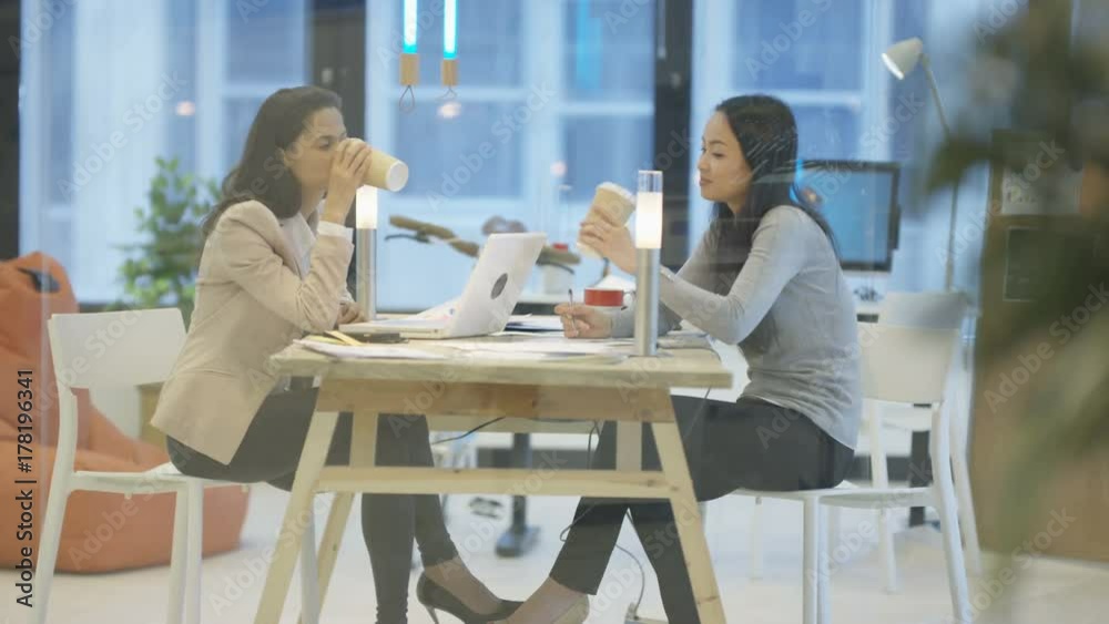 Confident successful businesswomen in a meeting looking over paperwork Confident successful businesswomen in a meeting looking over paperwork