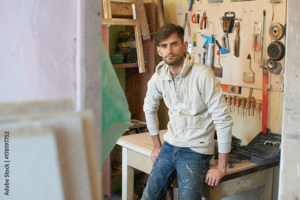 Portrait of a guy working in a home workshop.