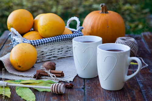 tea with lemon  honey  oranges  autumn leaves on woodenbackground