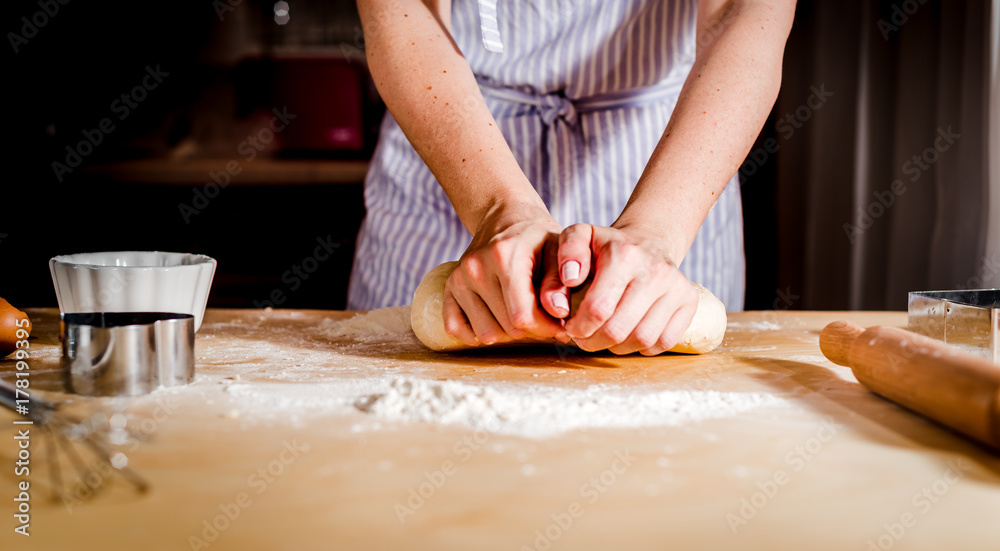 women's hands knead the dough on the table,