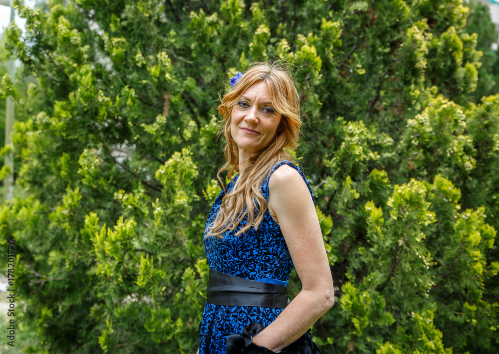 Blond woman in front of a tree smiles placidly Blond woman in front of a tree smiles placidly