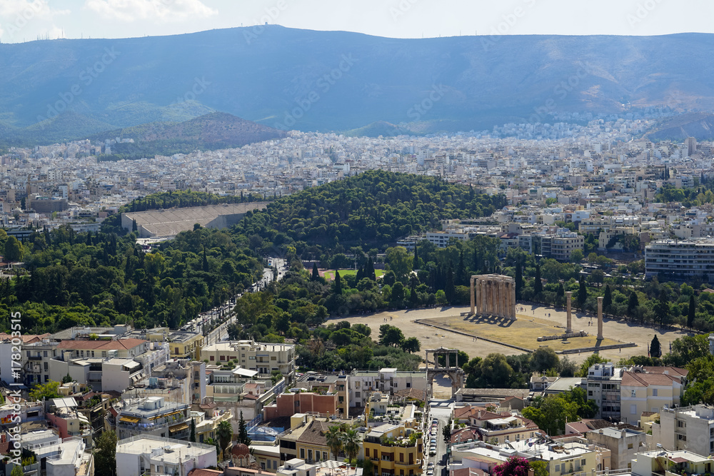 View of Athens city from Acropolis showing ancient ruin, buildings architecture, urban streets, green trees and mountain background