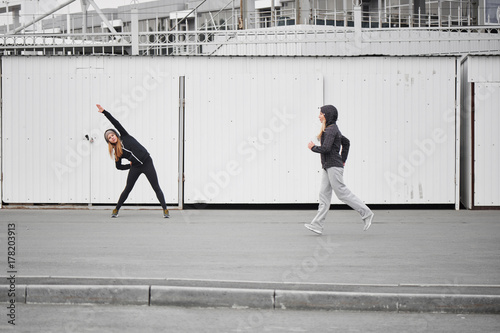 Two girls athletes perform exercises on the street. Friend lead a healthy lifestyle
