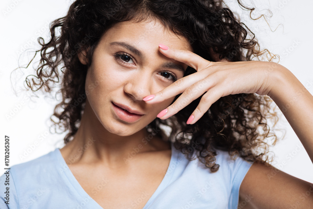 Close up of curly woman posing with fingers near eye Close up of curly woman posing with fingers near eye