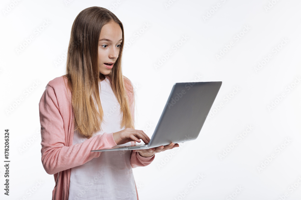 Cute teenage girl looking surprised while reading email Cute teenage girl looking surprised while reading email