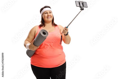 Overweight woman holding an exercise mat and taking a selfie
