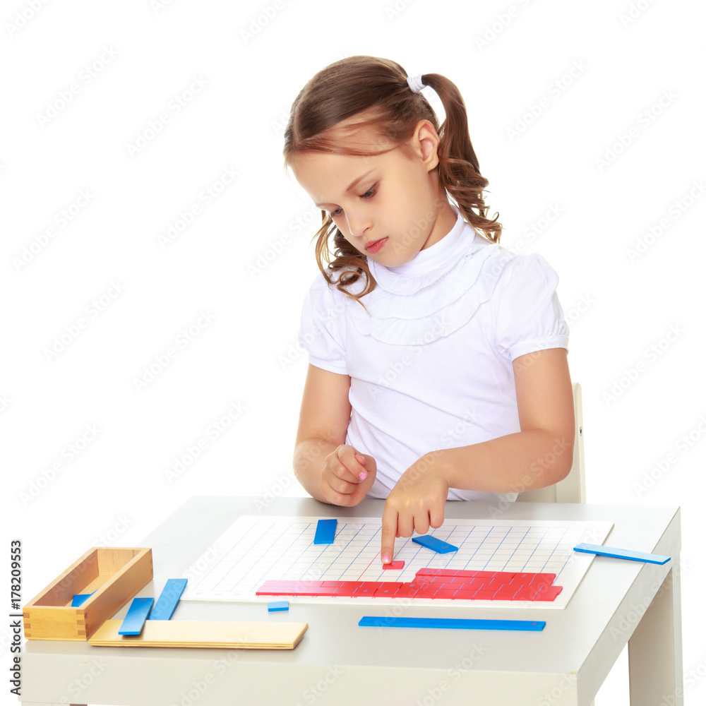 A little girl is studying Montessori stuff.