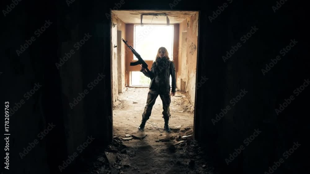 Young attractive military woman holding automatic rifle and looking at camera. Young attractive military woman holding automatic rifle and looking at camera.