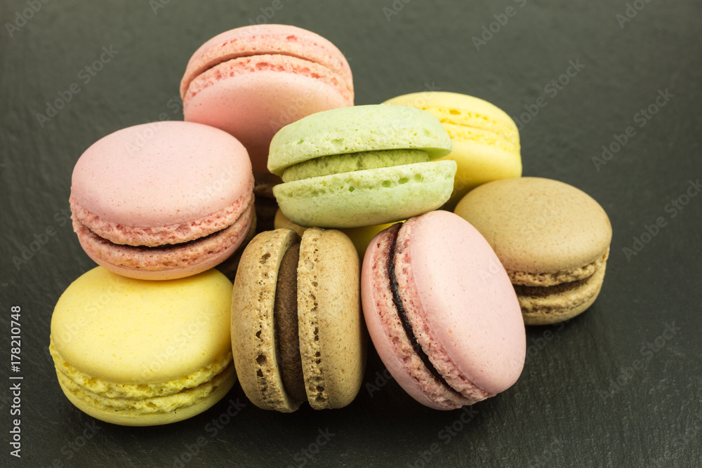 french sweet macarons in pink, yellow, green and brown on slate plate french sweet macarons in pink, yellow, green and brown on slate plate
