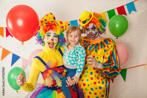a terrible clown and a good clown with a child. Halloween. The crazy clown and clowness. Little girl