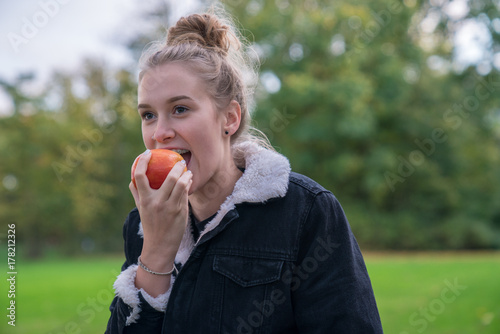 Eine junge Frau isst einen Apfel im Park