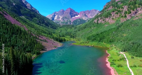 Mountain Lake With Purple Peaks In Green Valley - Approaching Aerial View - Maroon Bells, Colorado, USA