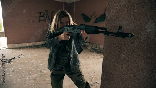 Young attractive military woman holding automatic rifle and looking at camera. photo