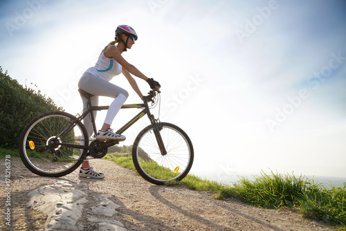 Woman in sports outfit riding bike on country track © goodluz