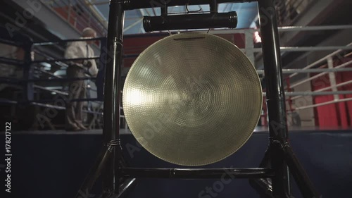 Male hand with hammer banging a native golden gong in slowmotion. Beginning, start concept.