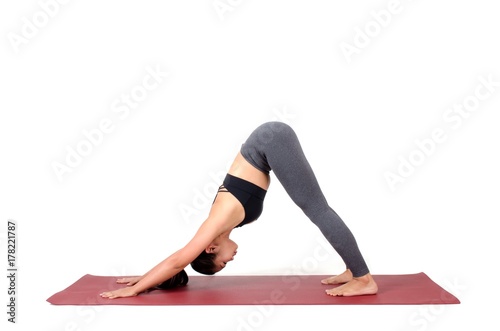 young asian woman doing yoga in Adho Mukha Svanasana or Downward-Facing Dog yoga pose on the mat isolated on white background, exercise fitness, sport training, healthy lifestyle and people concept