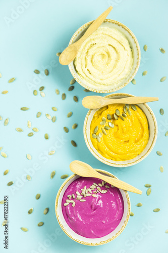 bright appetizers in the form of sauces on a blue background among pumpkin seeds. Hummus  carrot and beetroot sauces. Top view. Flat lay