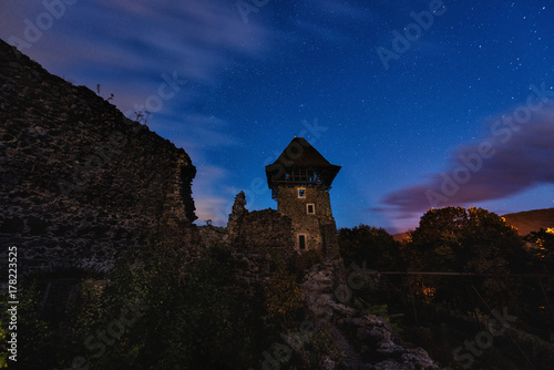 Ruins of medieval castle at night with amazing starry sky and clouds, mystical place, Nevytsky castle, Transcarpathia, Ukraine