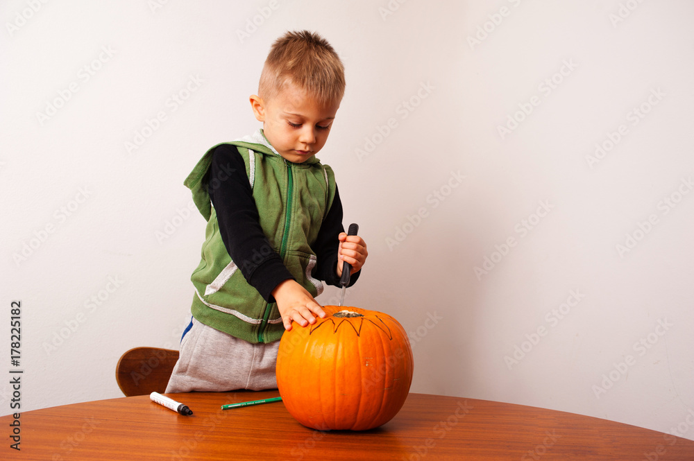 Fototapeta premium a kid has fun in the preparation of a terrifying halloween pumpkin
