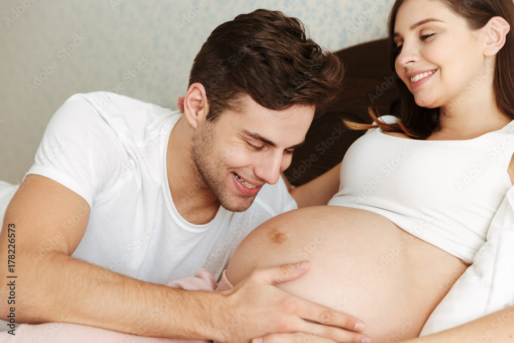 Happy pregnant wife lying in bed with her husband