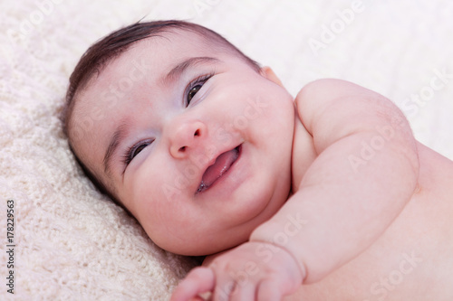 Cute, pretty, happy, chubby and smiling baby girl portrait, laughing with a big smile. Naked or nude on fluffy blanket. Four months old