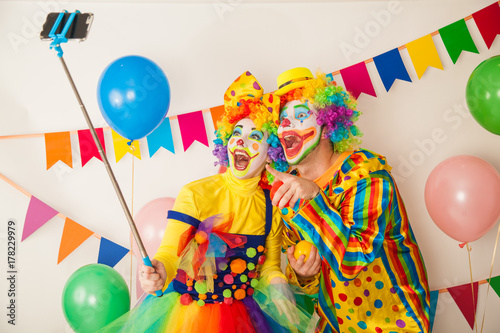 Two clowns boy and girl on Holiday with a selfie stick. Birthday of the child.