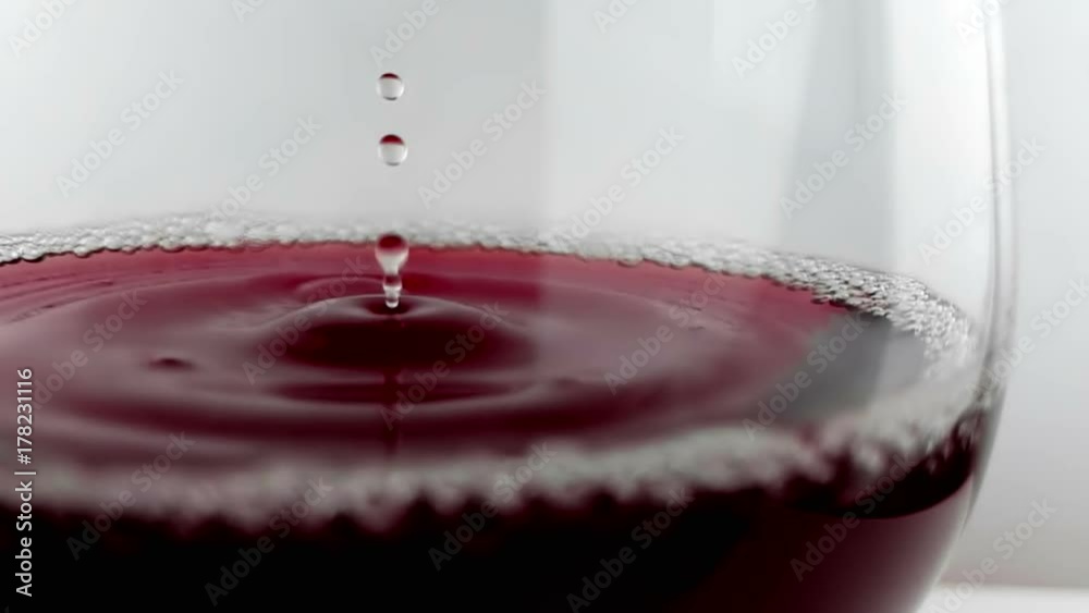 red wine drop falling down into drink glass on white background, nutrition health-care concept, shooting with high speed camera in slow motion