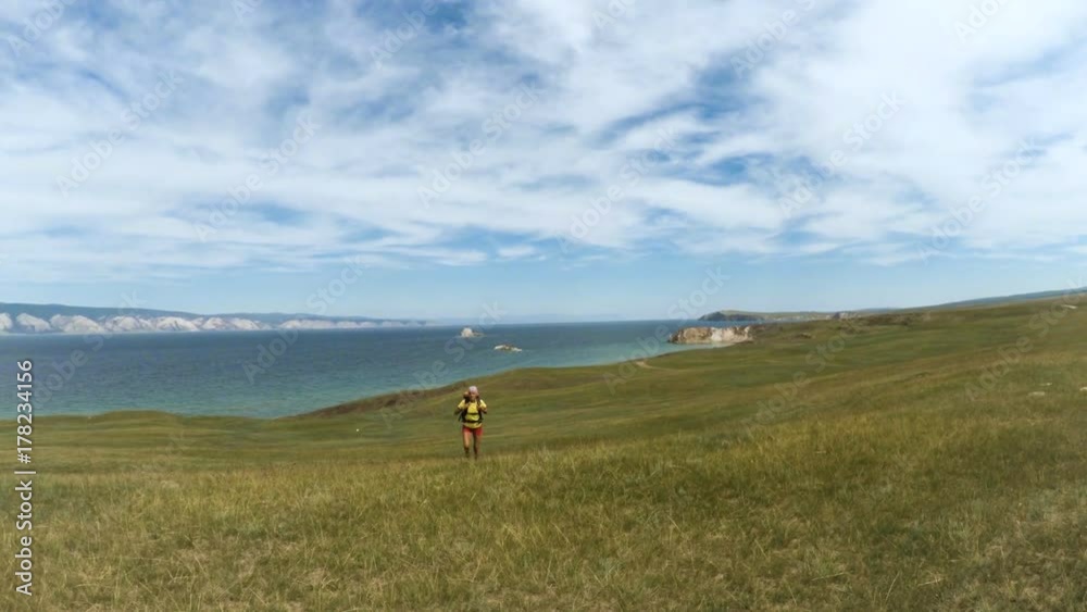 Woman hiker trekking on walking along blue lake. Wearing backpack. Healthy lifestyle Caucasian girl in Siberia in summer, Russia Woman hiker trekking on walking along blue lake. Wearing backpack. Healthy lifestyle Caucasian girl in Siberia in summer, Russia