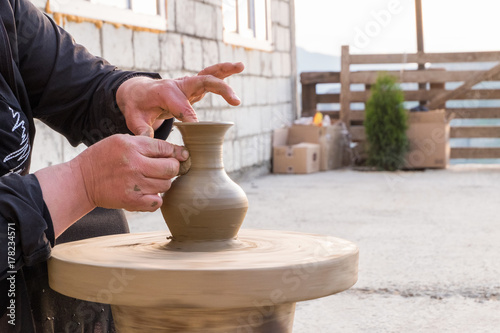 hands of a potter's woman make a pitcher of clay