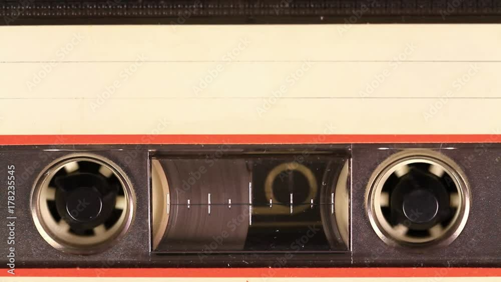 Macro static camera view of vintage audio cassette tape with a blank white label in use sound recording in a cassette player. Cassette Tape with a white blank label