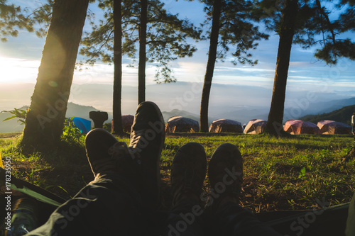 Feet of two friends or a couple in the entrence of a tent while watching the sunrice. Trekking, camping, nature, outdoors concept. Copy space photo