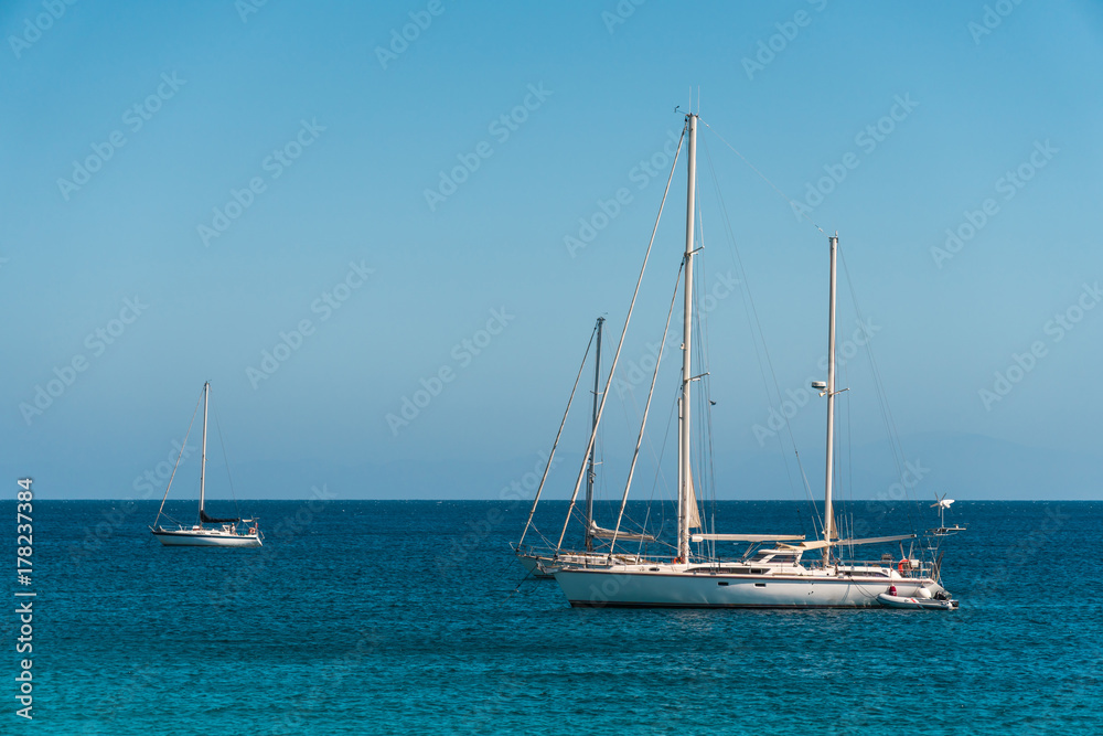 Three anchored yachts in the blue sea