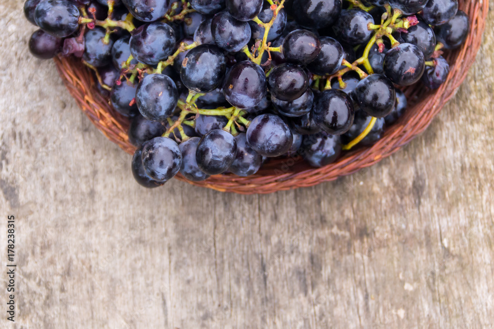 Ripe grapes in wicker basket on wooden table