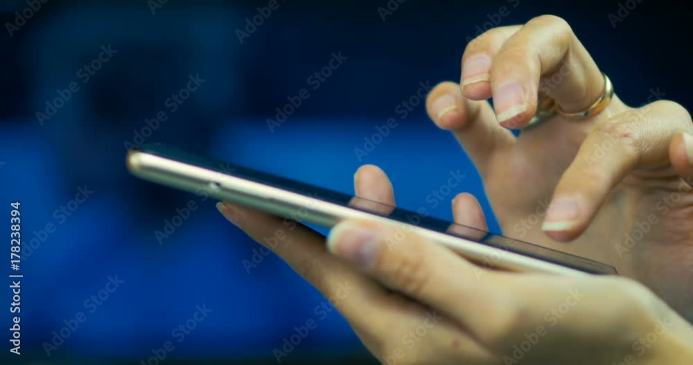 Close-up of a young girl browses pages on the internet on smart-phone on a laptop screen background.