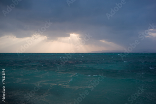 雲から夕陽が覗く海