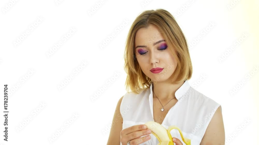 A woman is eating a banana. Beautiful girl on a white background. A woman is eating a banana. Beautiful girl on a white background.