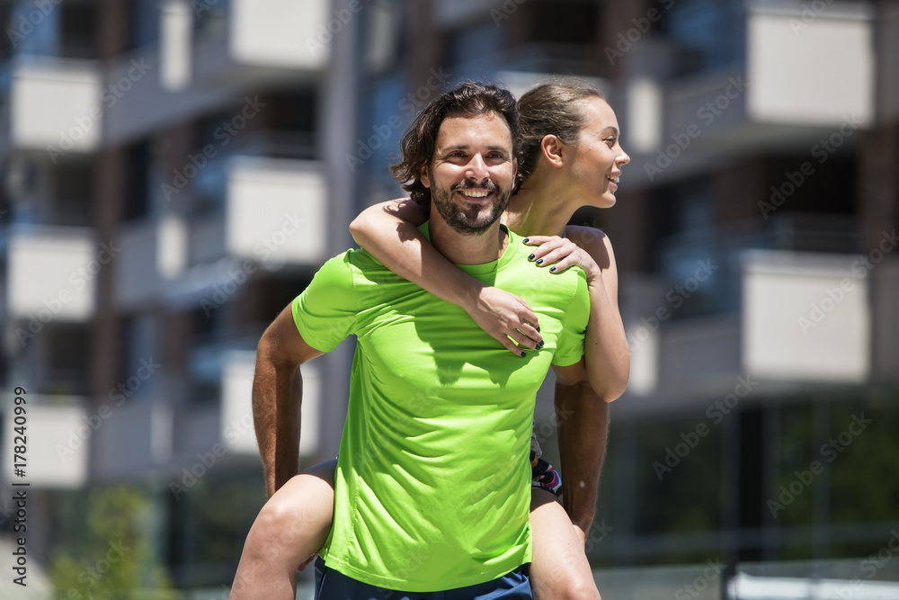 Sportsman holding sportswoman on his back outdoor