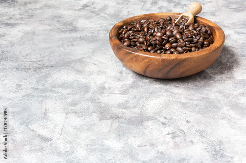 Coffee beans in a wooden bowl on a light marble background with copy space in a minimalist style