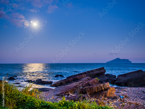 The beauty moment of moon nature and sea. The great supermoon is shining above the Pacific ocean. The moonlight is so strong, the light reflect to the sea in long and wide way toward the rocky shore