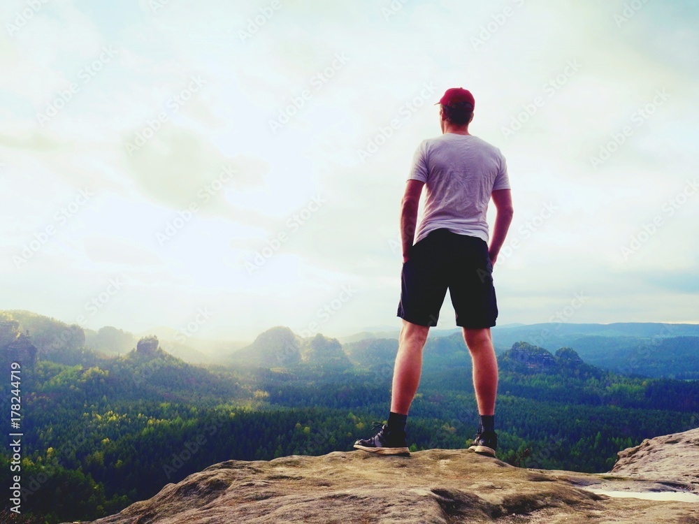 Man in t-shirt and pants. Tourist on mountain peak looking into landscape. Man in t-shirt and pants. Tourist on mountain peak looking into landscape.