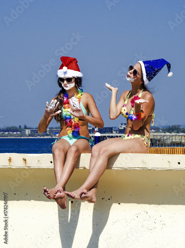 Two girlfriends in a Santa hat and in the image of a pirate during a beach holiday.