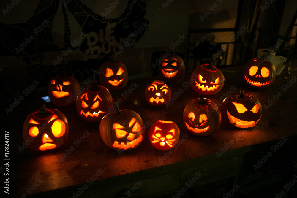 Soft focus shot of halloween pumpkins lined up on table in thematic cafe or big family house. Candles lit up inside for spooky and evil effect, atmosphere of autumn holiday