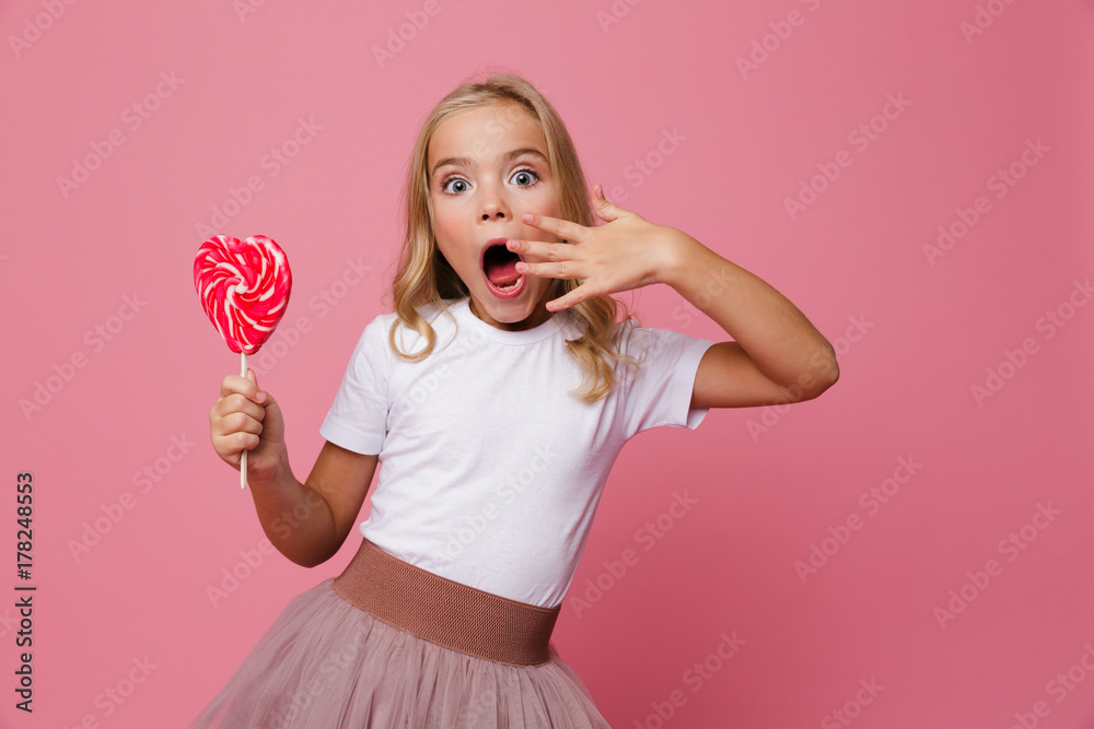 Portrait of a surprised little girl holding heart shaped lollipop Portrait of a surprised little girl holding heart shaped lollipop