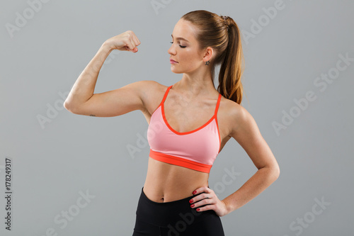 Amazing young sports woman showing biceps.